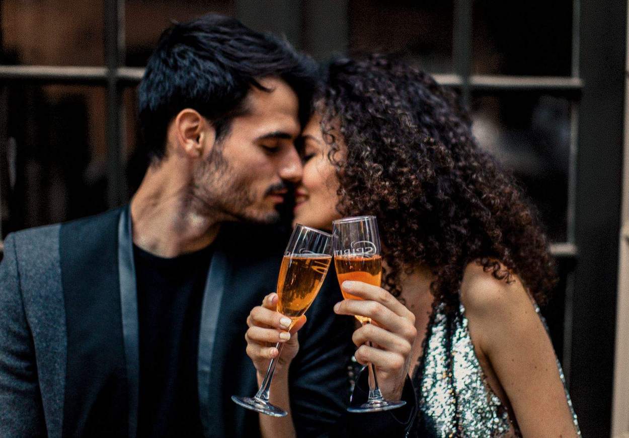 Couple touching foreheads and clinking champagne flutes in front of black-paned doors, Old Town Alexandria engagement photographer.