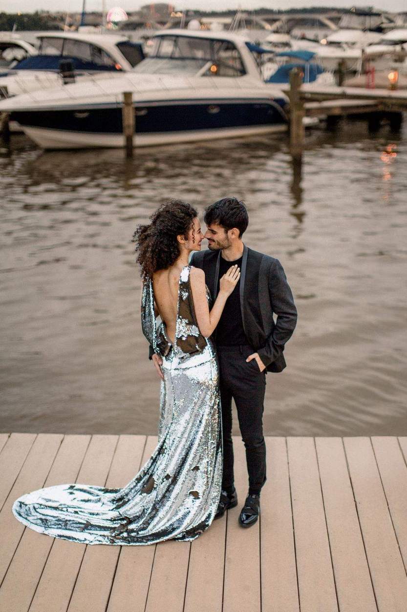 Engagement photos on a dock in Old Town Alexandria: a couple nose to nose, her silver sequin gown trailing across the boards.