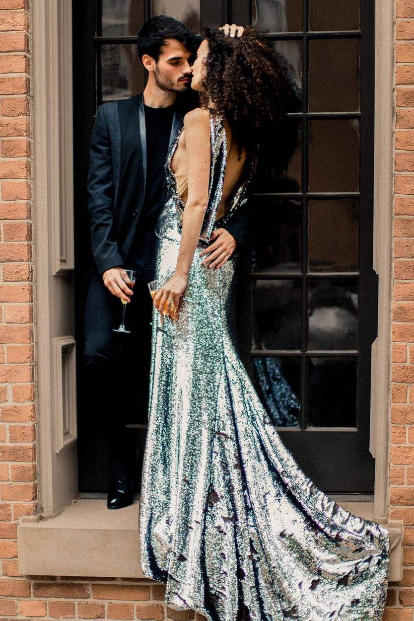 Couple kissing in a brick doorway in Old Town Alexandria, her open-back sequin gown trailing along the stone ledge.