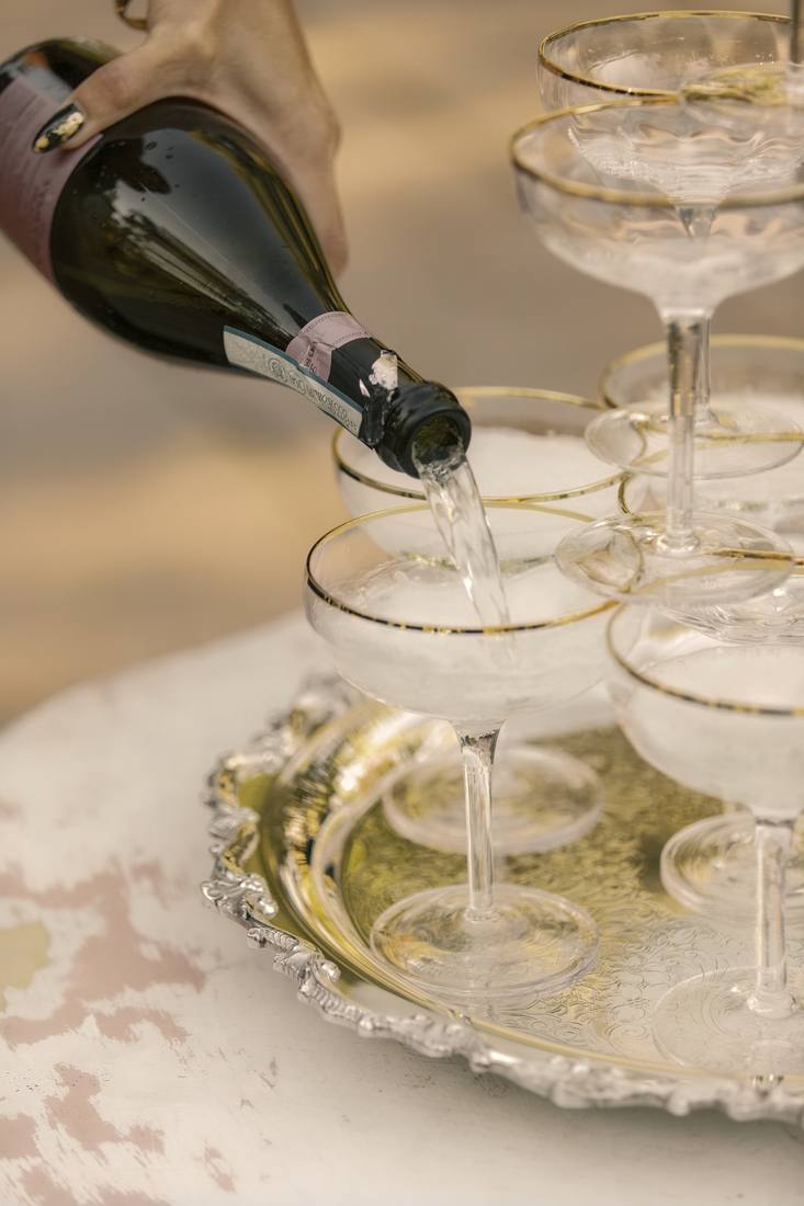 Prosecco poured into a tower of gold-rimmed coupe glasses on a silver tray