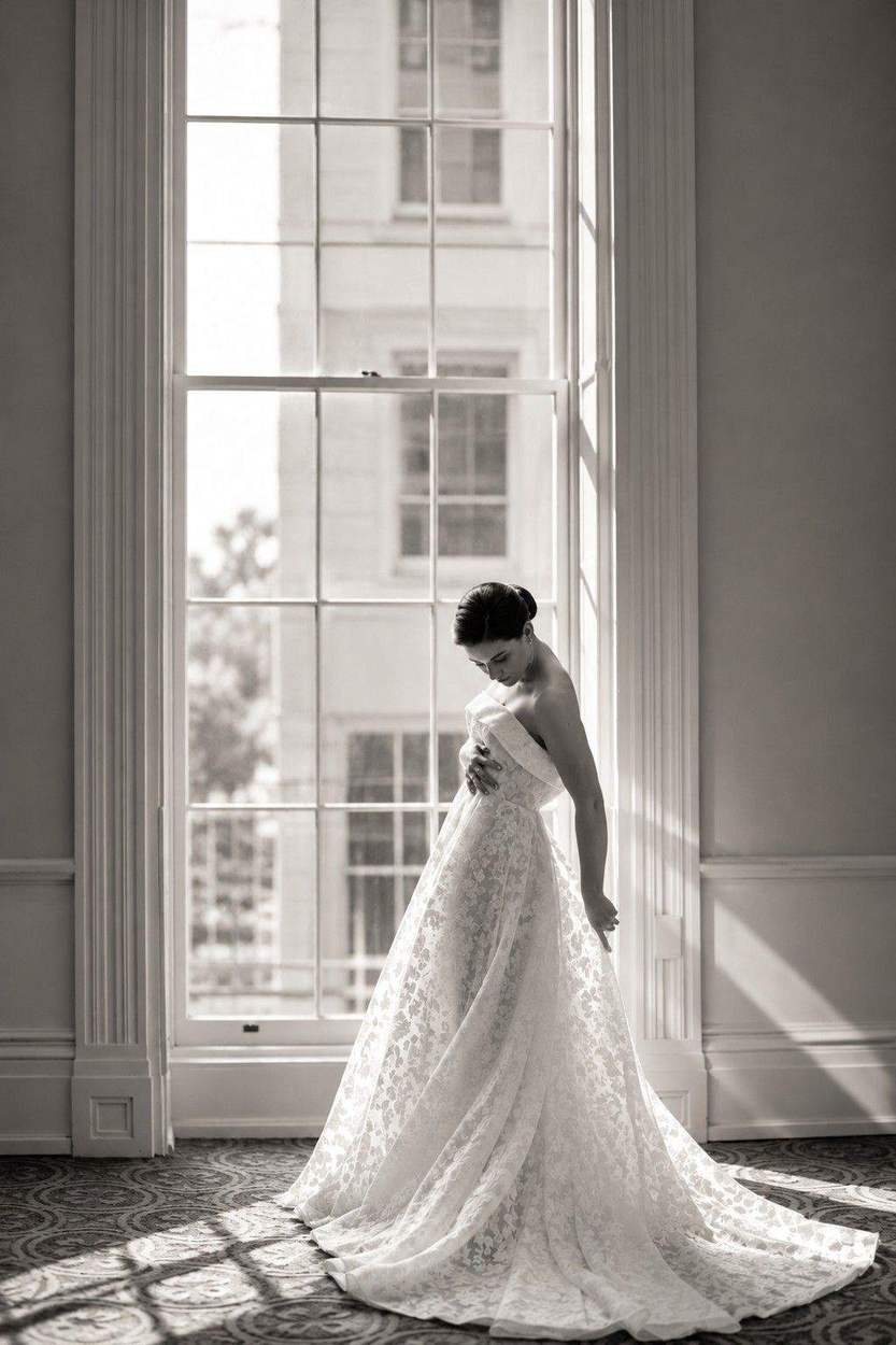 Washington DC photographer black and white bridal portrait: a bride in a lace gown beside a tall window in a historic room.