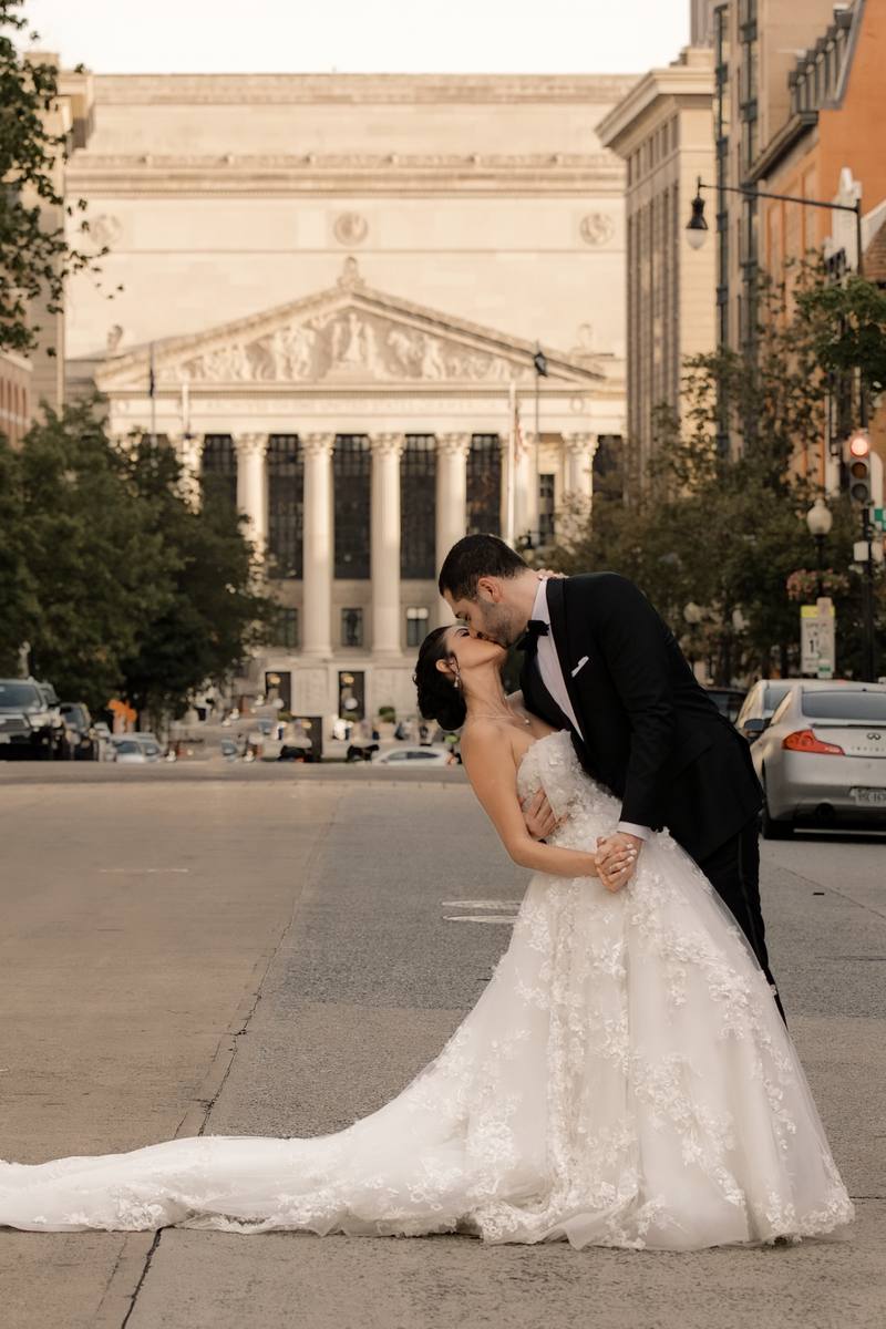 Groom dipping the bride for a kiss in the middle of a downtown Washington DC street, a columned classical building at the end of the road