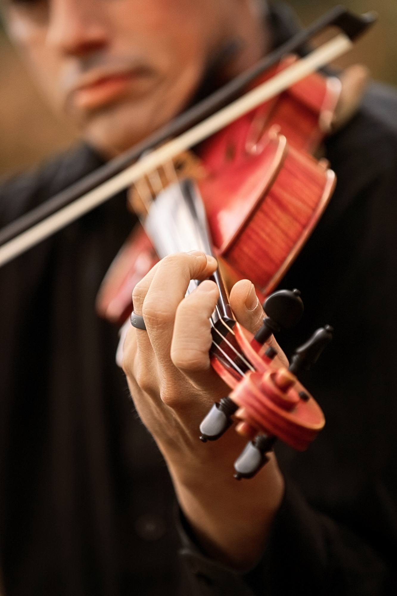Close view of a violinist's fingers on a red violin