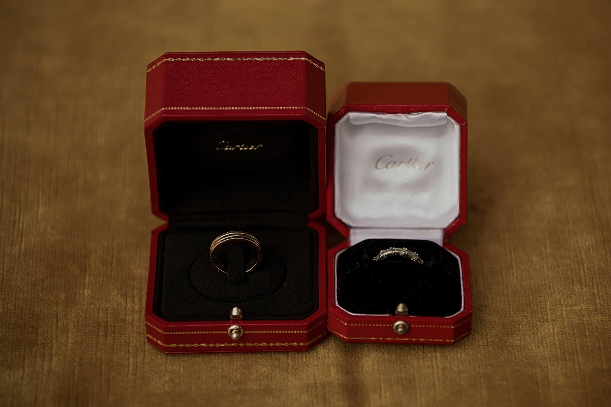 Two wedding bands in open red ring boxes on gold velvet